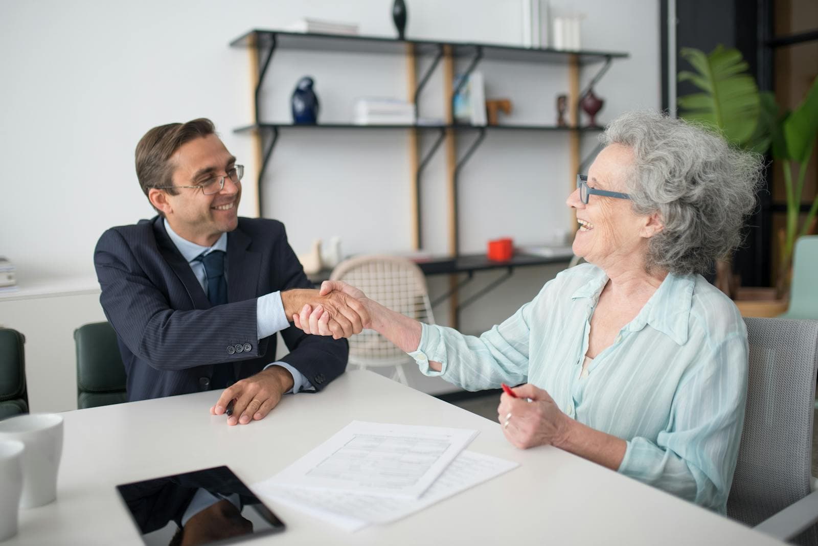 An elderly woman consults with a professional advisor at a desk — the moment of vetting a trusted senior care provider.